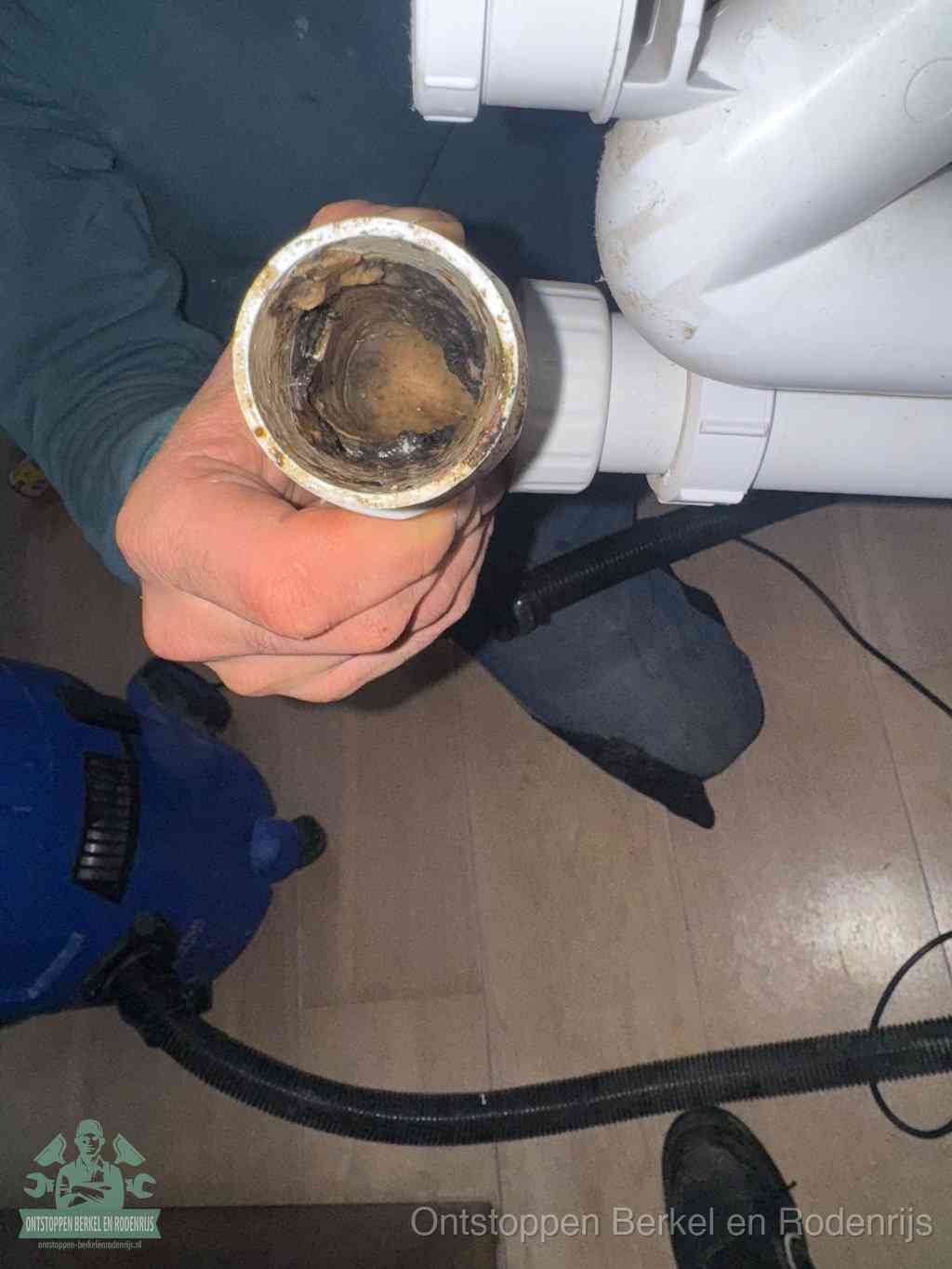 Een losgekoppeld PVC-afvoerbuisstuk dat van binnen volledig is dichtgeslibd met vet en vuil, de meest voorkomende oorzaak van verstoppingen in Berkel en Rodenrijs