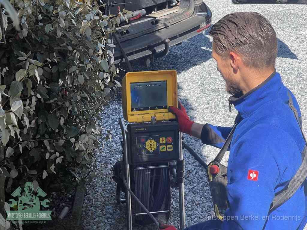 Een monteur bedient een rioolinspectiecamera met monitor en haspel om de verstopping in beeld te brengen in Berkel en Rodenrijs