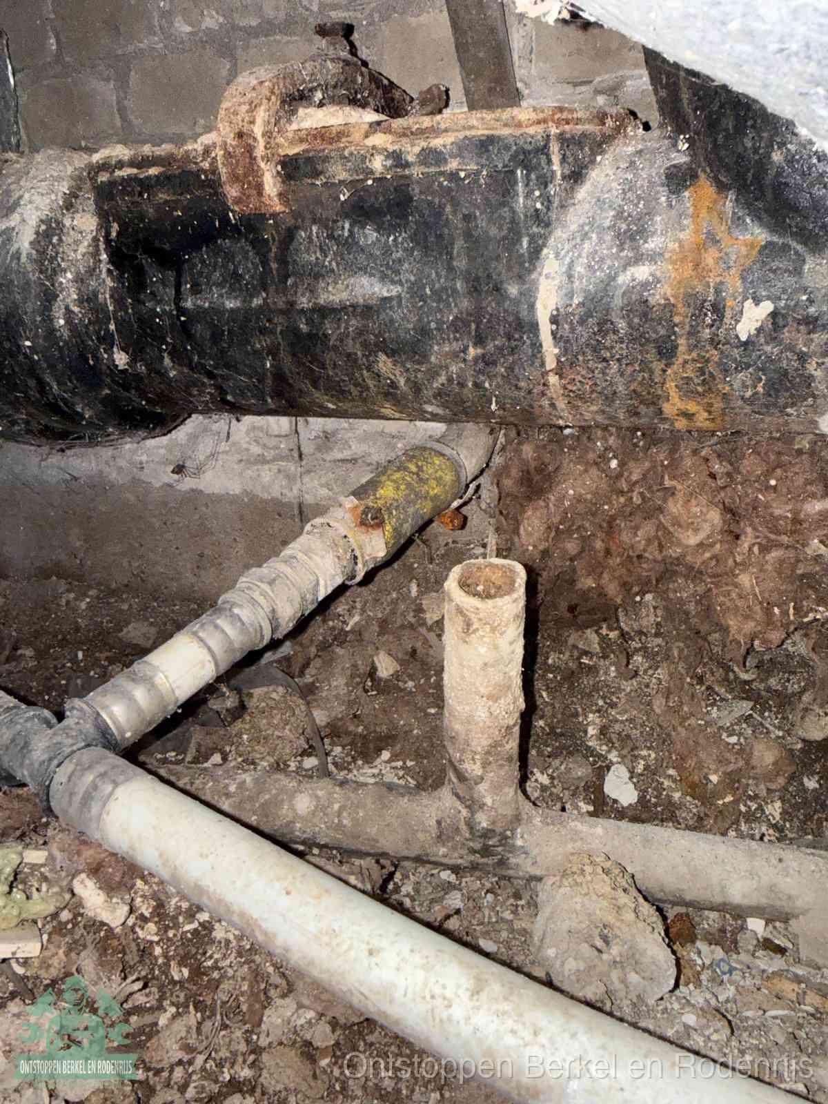 Een oude hoofdrioolbuis met roest- en kalkaanslag in een kruipruimte, oorzaak van terugkerende structurele rioolproblemen in Berkel en Rodenrijs